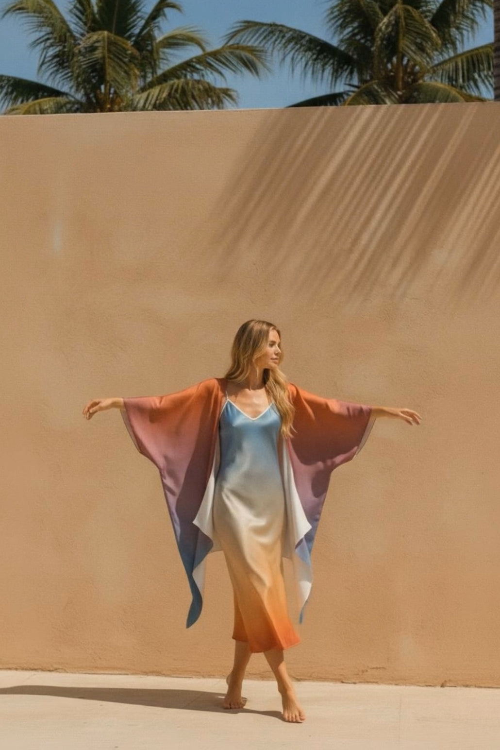 Woman in a colorful kimono standing in front of a sand dune with palm trees in the background