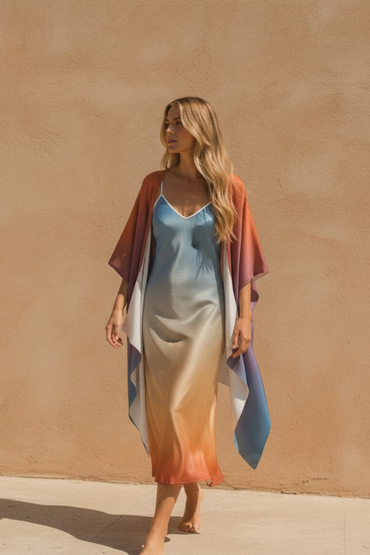 Woman wearing a colorful dress with a matching shawl against a beige wall.