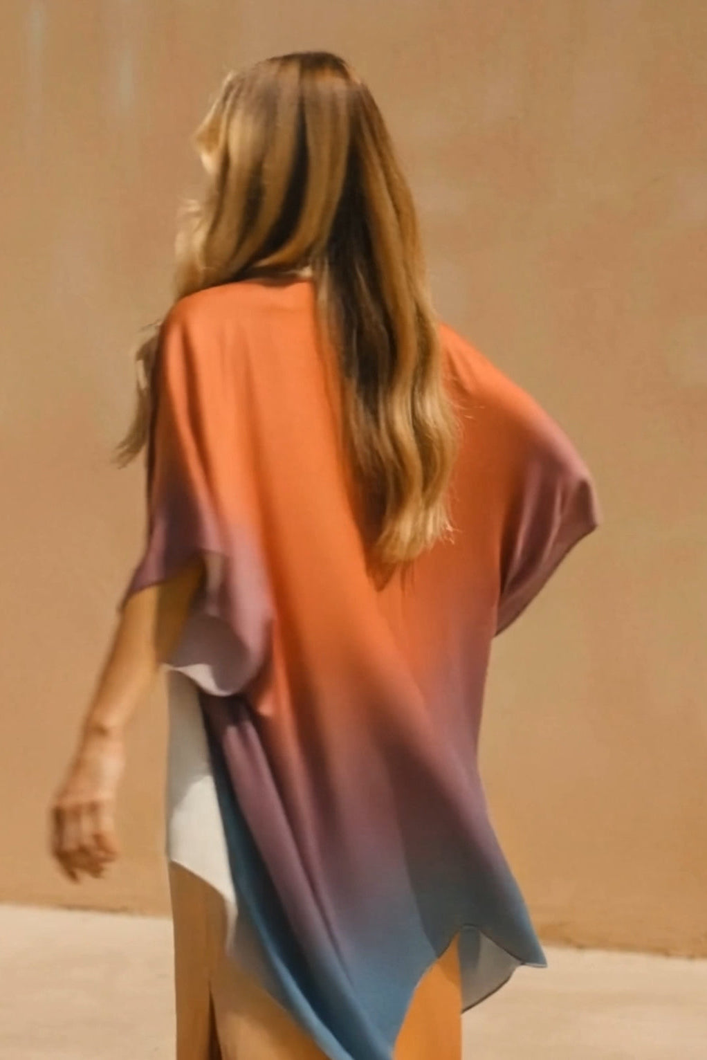 Woman wearing a colorful dress with an ombre effect against a beige background