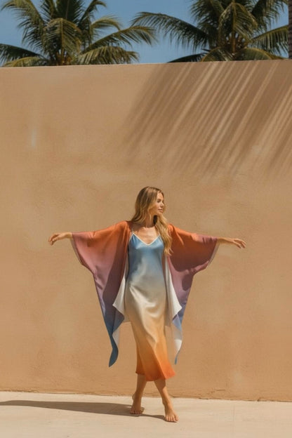 Woman in a colorful kimono standing in front of a sand dune with palm trees in the background