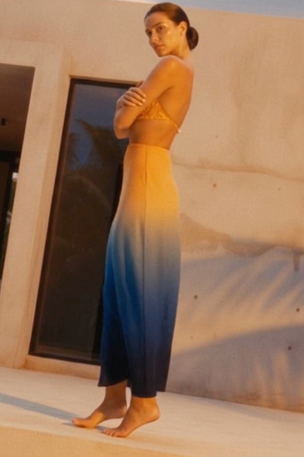 Woman in a gradient dress standing in front of a modern building.