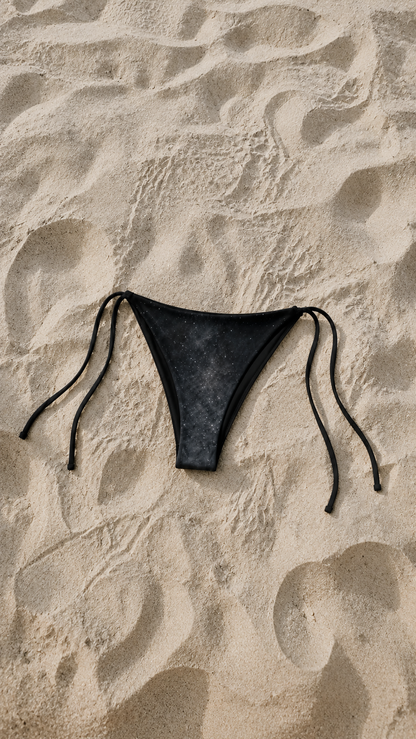 Black bikini bottom on sand