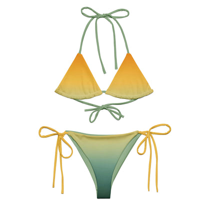 Model wearing a yellow-to-green ombré string bikini under plumeria flowers, sustainable recycled swimwear, Holding Court Horizons collection.